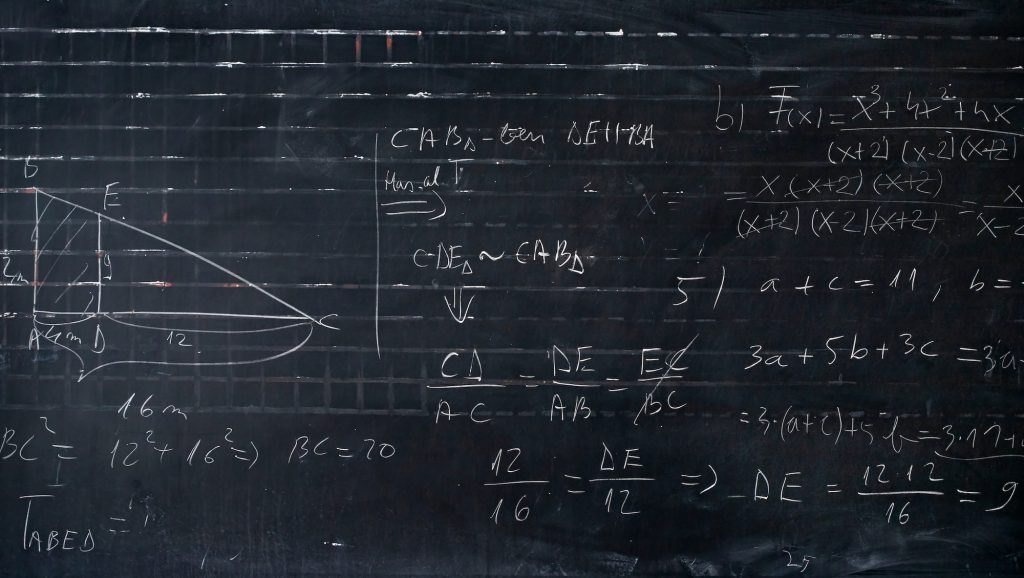 Maths formulas written by white chalk on the blackboard background.