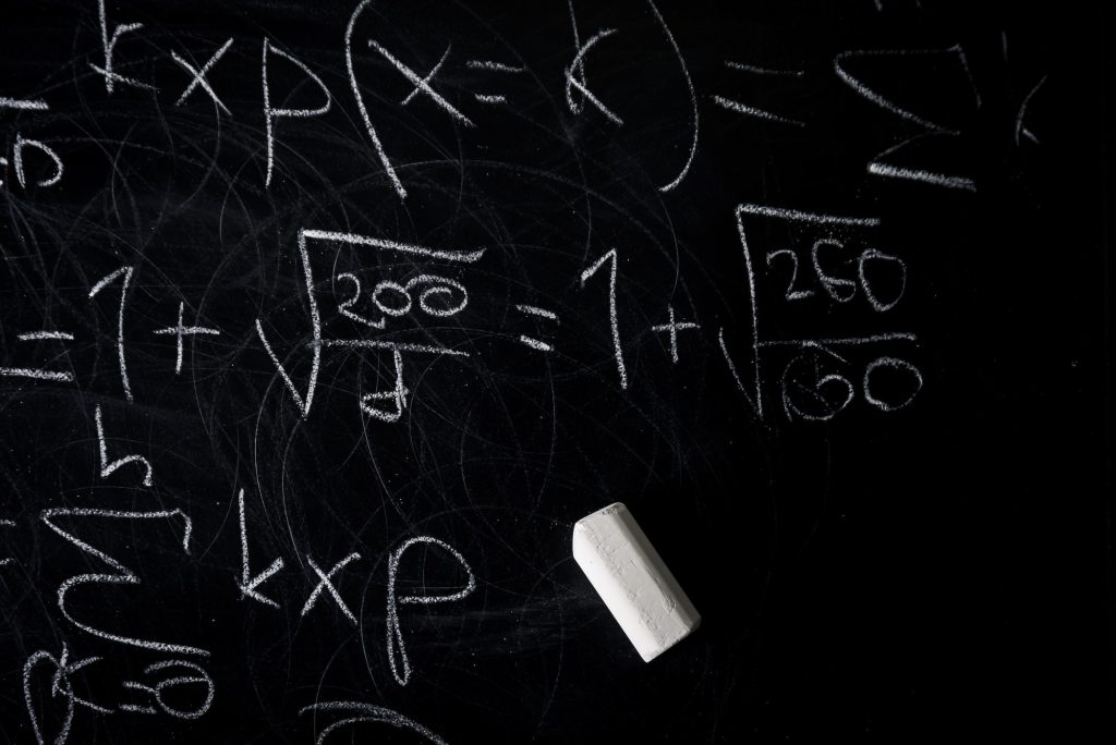 Part of maths formulas written by white chalk on the blackboard background.